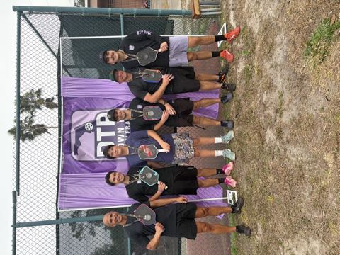 Six medalists lined up with paddles at a DTP Down To Pickleball tournament